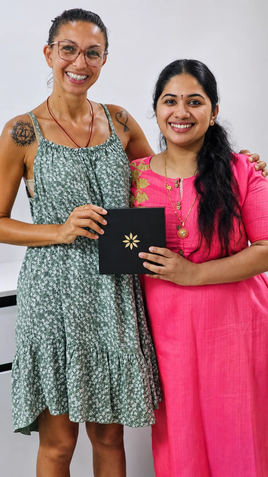 A visiting patient and Dr. Pournami holding up a clear-aligner case together