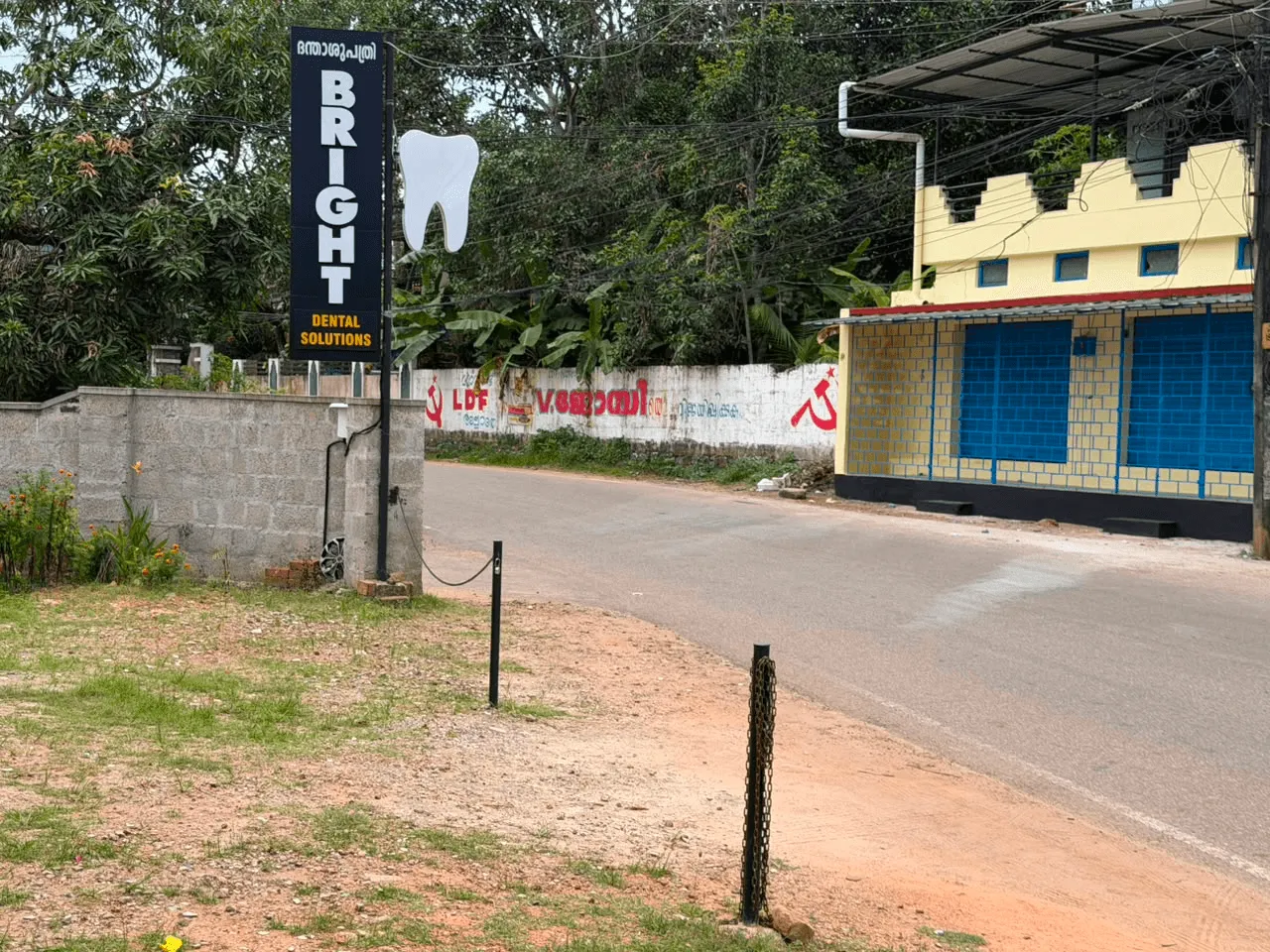 The tall Bright Dental Solutions sign with its tooth logo standing at the roadside in Varkala