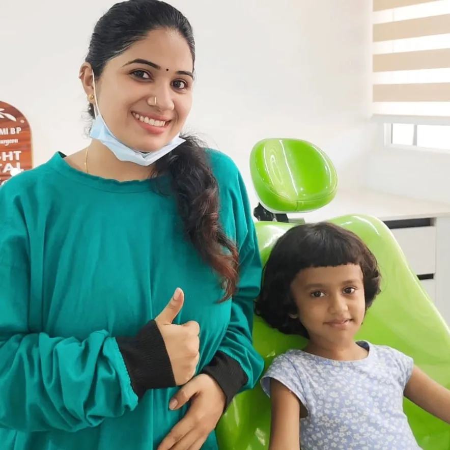 A young girl sitting calmly in the dental chair beside her smiling dentist