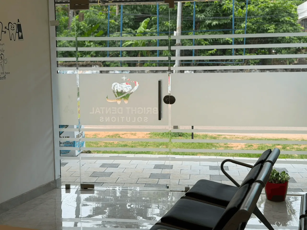 Glass entrance doors of the clinic seen from inside, etched with the Bright Dental Solutions name
