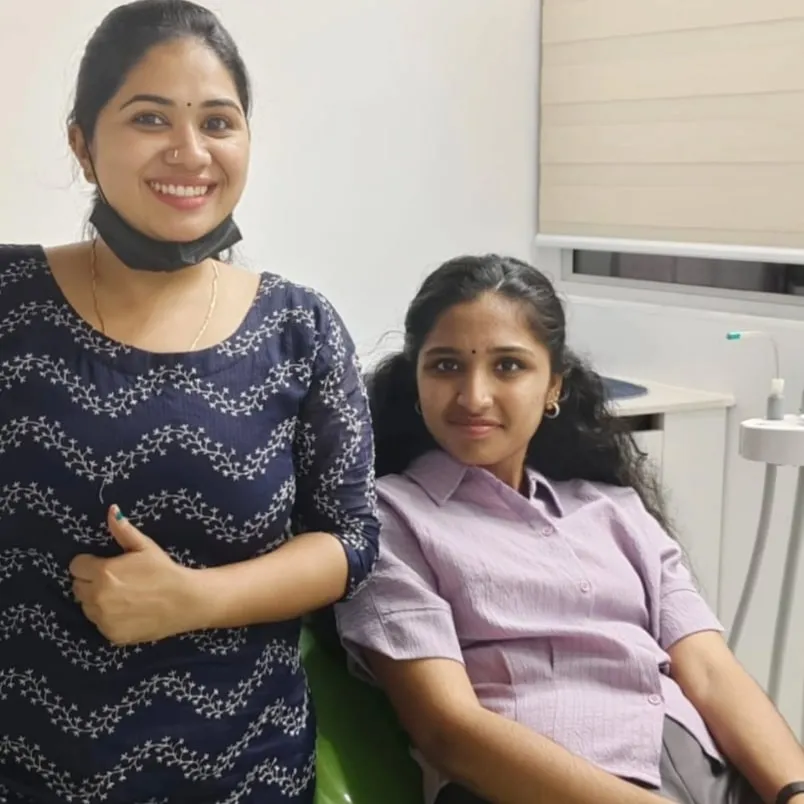 A teenage patient relaxed in the dental chair with her dentist beside her