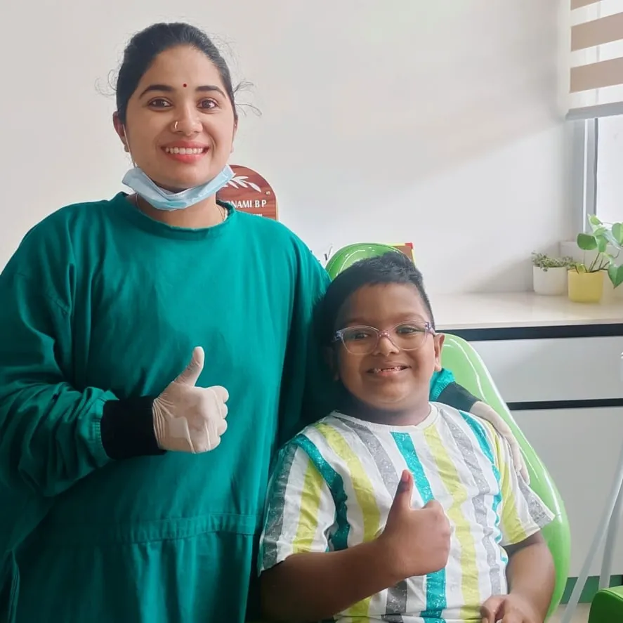 A dentist and a boy wearing glasses both giving a thumbs-up after his check-up